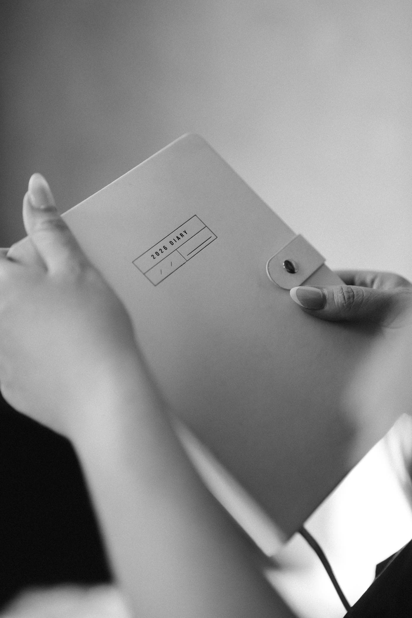 Hands holding an open notebook, black and white.